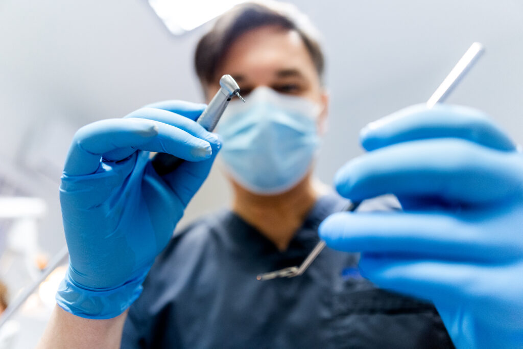 Zdjęcie przedstawia stomatologa trzymającego sondę periodontologiczną